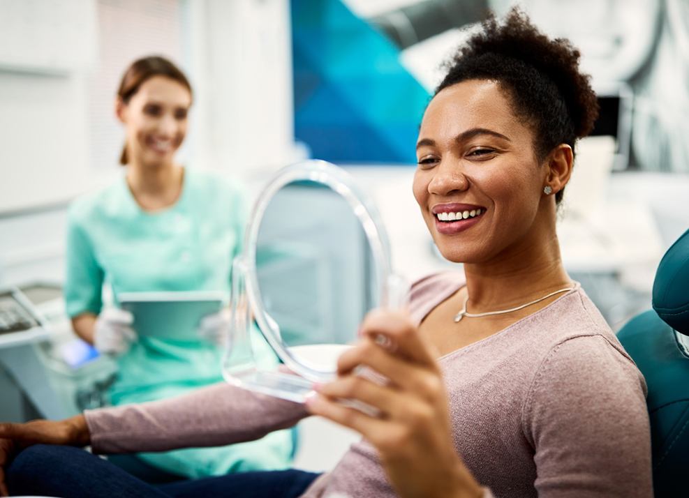 Woman holding mirror, admiring her new smile