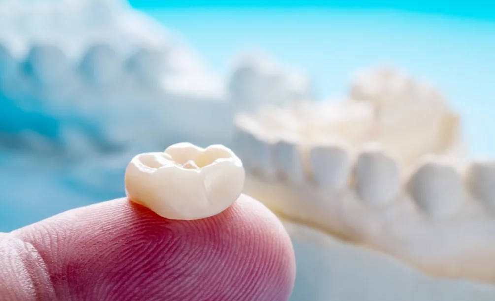 Person holding a dental crown on their finger