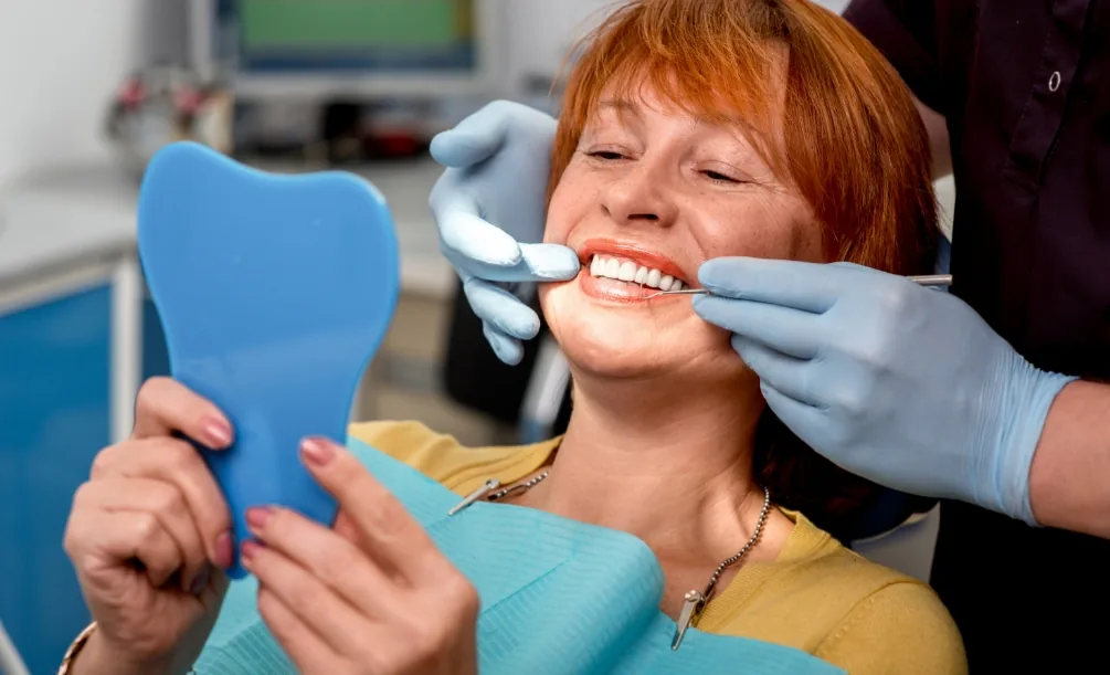 Woman looking at her smile in a dental chair mirror
