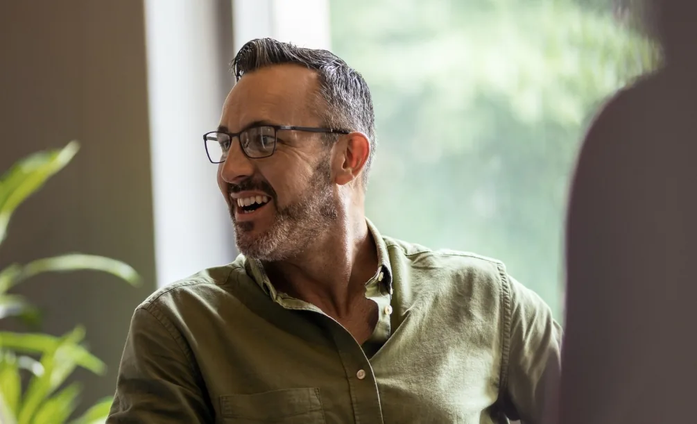 Smiling man in glasses and a dark green button-up shirt