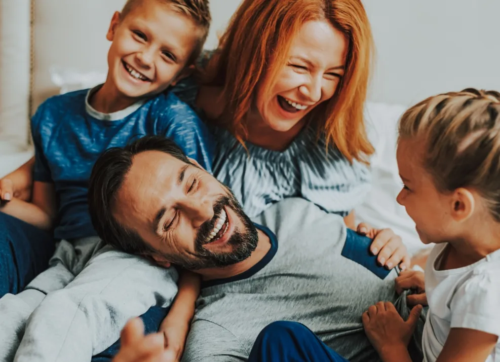 Family of four cuddling on a couch and laughing together