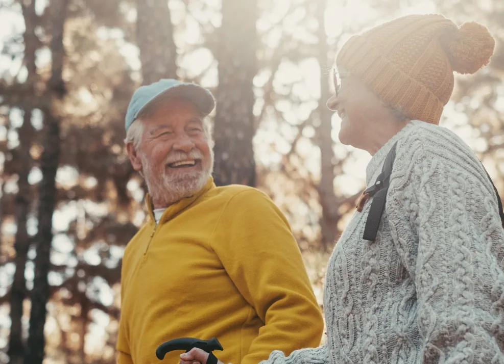 Happy senior man and woman walking through the woods together on a sunny day