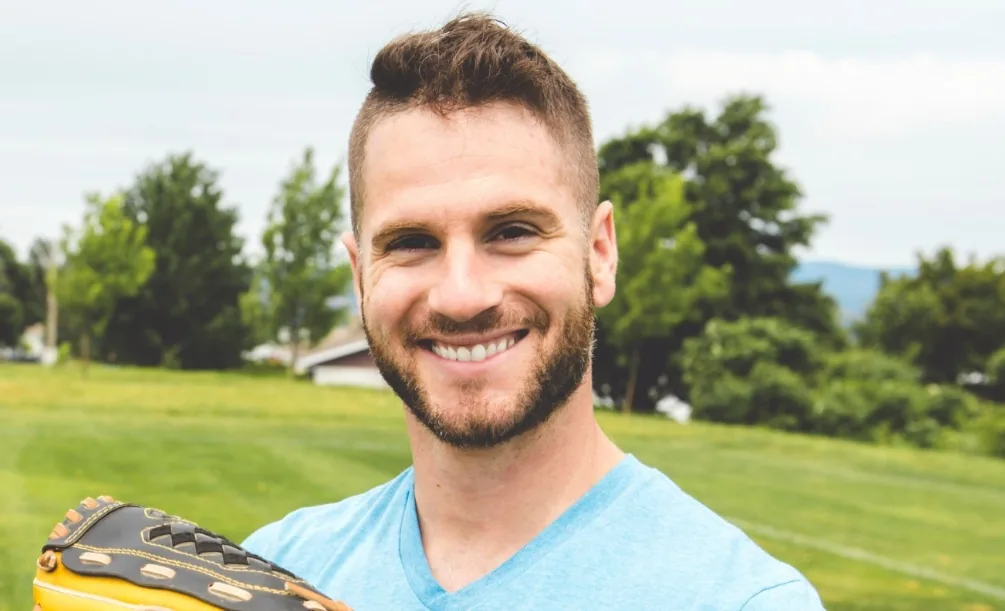 Man smiling outdoors in a green field