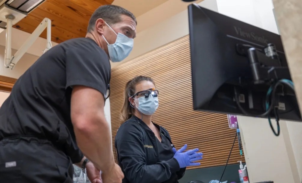 Two dentists viewing a computer screen in a treatment room