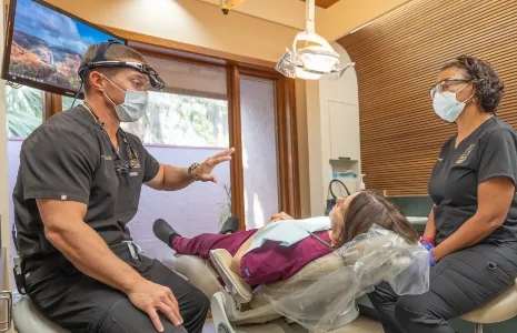 Dentist and assistant talking to a patient in dental chair
