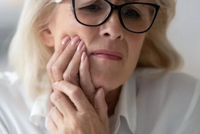 Woman holding her jaw because of tooth pain