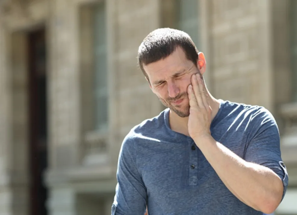 Man experiencing jaw pain outdoors