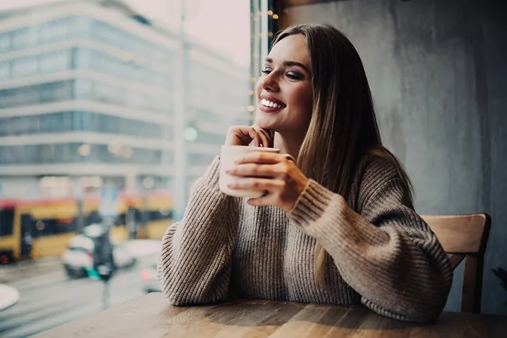 Woman smiling while holding a coffee cup