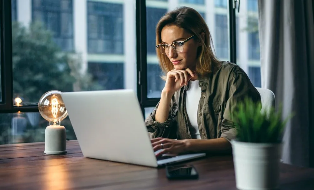 Woman sitting at a table reading on her laptop