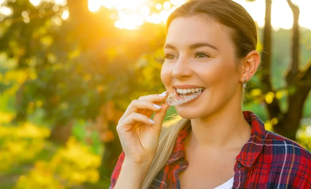 Young woman placing an Invisalign aligner over her teeth